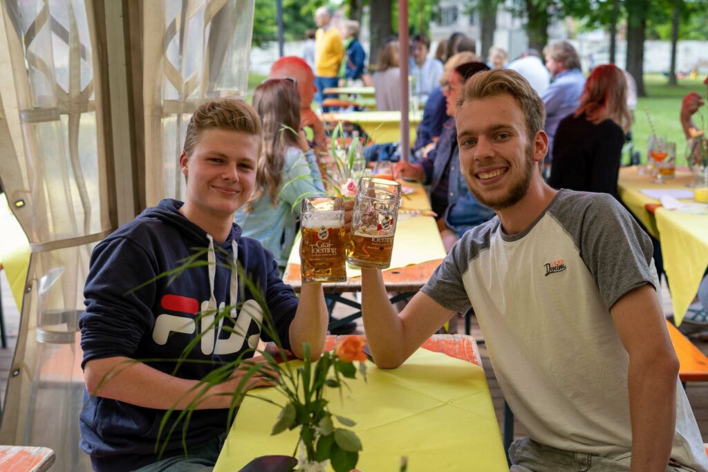 Personen stoßen mit Bier an beim COPLAN Sommerfest